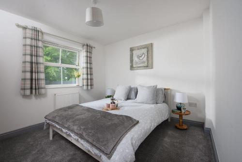 a bedroom with a large white bed with a window at Hoopers Lodge, Croft Hooper, Crowlas in Ludgvan