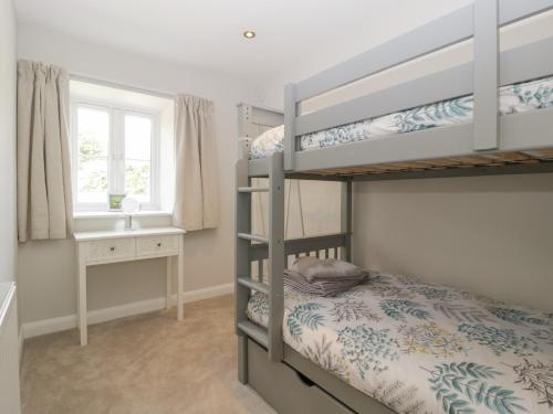 a bedroom with bunk beds and a desk and a window at The Old School in Cinderford