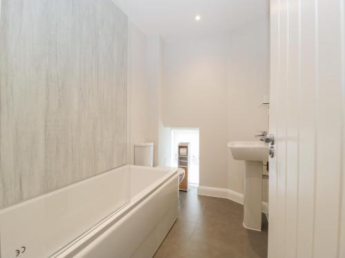 a white bathroom with a tub and a sink at The Old School in Cinderford