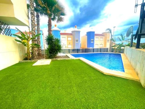 une cour avec une piscine et de l'herbe verte dans l'établissement 2 bedroom infinity beach., à Mazarrón