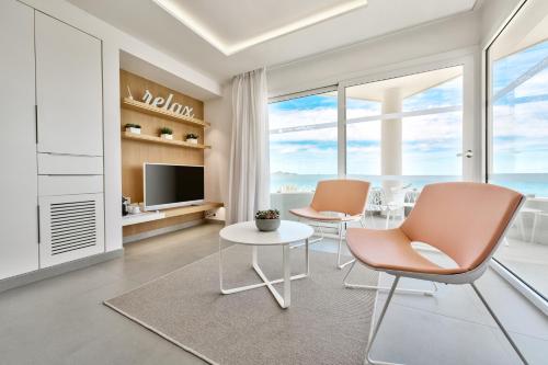 a living room with two chairs and a table and a tv at Hotel Garbi Ibiza & Spa in Playa d'en Bossa