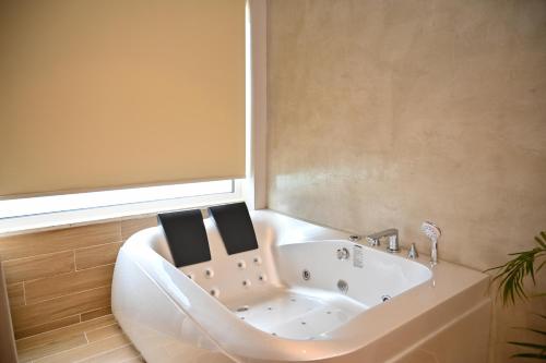 a bathroom with a bath tub with two mirrors at Hotel Zanzi in Durrës