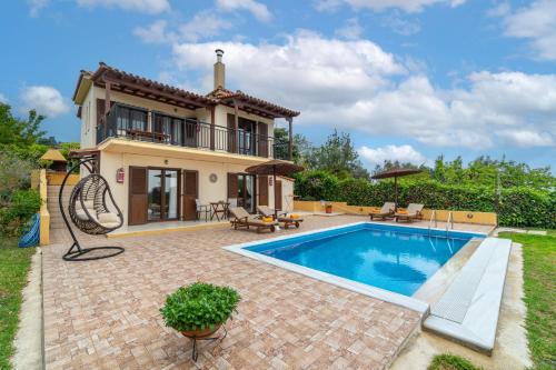 a villa with a swimming pool in front of a house at Villa Angela in Skiathos
