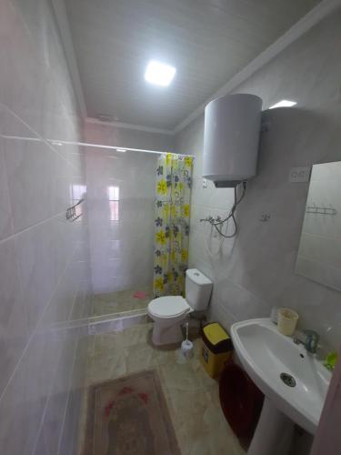 a white bathroom with a toilet and a sink at Salute guest house in Kaji-Say