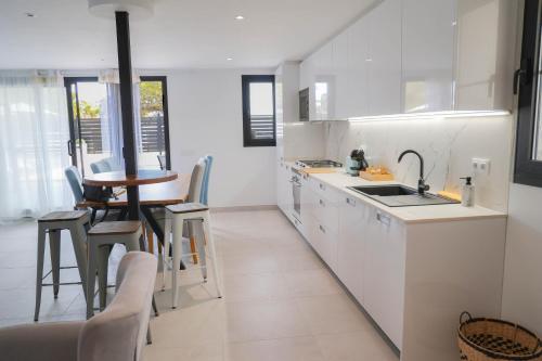 a white kitchen with a sink and a table at Villa de lujo EL MIRADOR in L'Ampolla