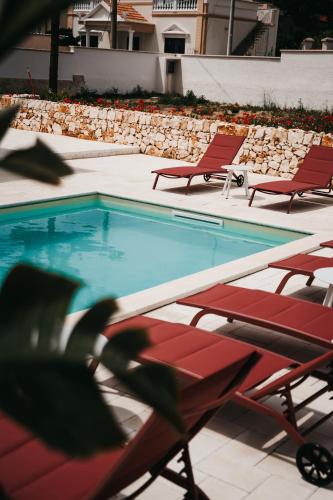 a swimming pool with red chairs and a row of chairs at Le canne Pool and Relax in Pulsano