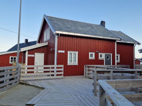 un granero rojo con una terraza de madera delante de él en Andøy Vest Rorbuer Reine en Reine