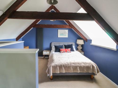 1 dormitorio con paredes azules y 1 cama con almohada roja en The Barn, en Plymouth