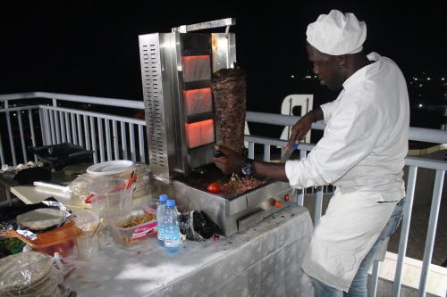 a man cooking food on a grill on a deck at Residence Le Carat Bonapriso in Douala