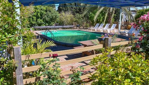 a swimming pool with a wooden bench next to at YalaRent Valley view Boutique cottages with Pool in Merhavyāh