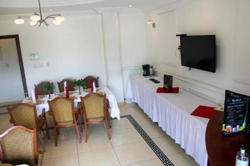 a dining room with two tables and a flat screen tv at Residence Le Carat Bonapriso in Douala