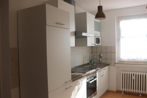 a kitchen with white cabinets and a sink and a window at Kölner Pension Apartments in Cologne