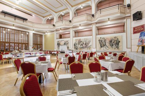 a dining room with tables and chairs and paintings on the walls at Hotel Patio Prague in Prague
