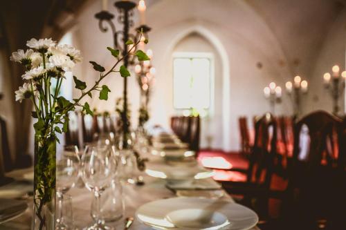 a long table with plates and glasses and flowers on it at Vadstena Klosterhotell Konferens & Spa in Vadstena