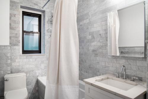 a bathroom with a sink and a shower curtain at Midtown East 2br w gym wd nr Grand Central NYC-1146 in New York