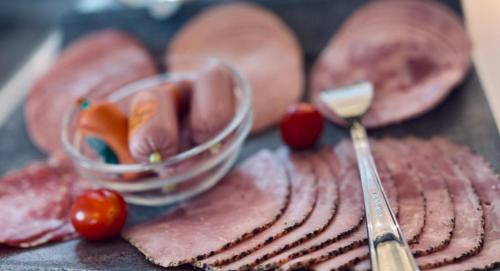 a tray with meats and a spoon of butter and tomatoes at Shipyard Guesthouse Gästehaus für Geschäftsreisende und Monteure an der Elsflether Werft und Trainingcenter Heinemann Solutions GmbH in Elsfleth