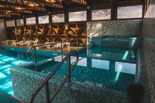 a swimming pool with chairs and tables in a building at Thermal Hotel Seven Seasons in Banya