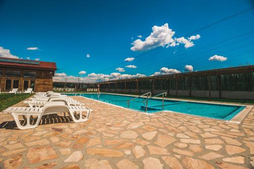 a swimming pool with white chairs next to a building at Thermal Hotel Seven Seasons in Banya