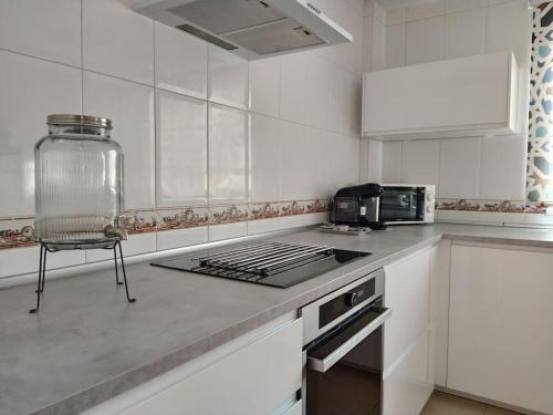 a white kitchen with a stove and a counter top at Luminosa y confortable casa con vistas y piscina in Jun