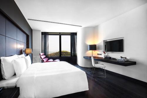 a hotel room with a white bed and a television at Shenzhen O Hotel in Shenzhen