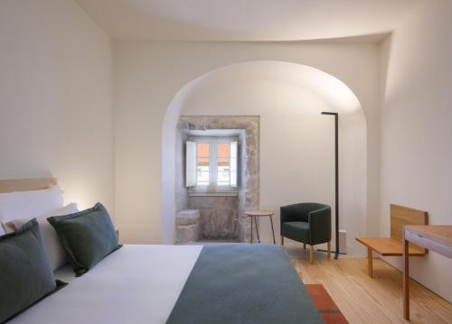 a bedroom with a bed and a desk and a window at Montebelo Mosteiro de Alcobaça Historic Hotel in Alcobaça