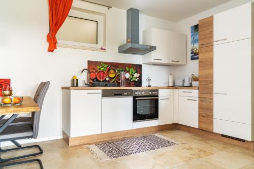 a kitchen with white cabinets and a wooden table at Urlaubsoase Hügelperle in Bad Gleichenberg