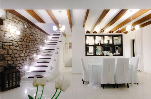 comedor con mesas blancas y pared de piedra en White Diamond Villa, en Kamena Vourla