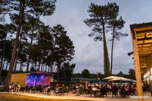 a crowd of people sitting at tables in front of a stage at Camping les dunes de Contis 3* grand emplacement ombragé et calme in Saint-Julien-en-Born