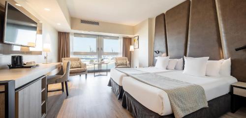 マラガにあるイルニオン マラガの大きなベッドとデスクが備わるホテルルームです。