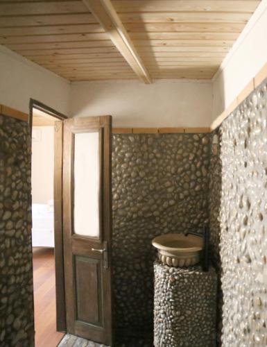 a room with a wooden door and a wall with rocks at Captain Ikaros in Agios Kirykos
