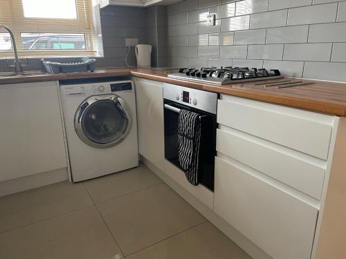 a kitchen with a stove and a washing machine at Garden Flat in London