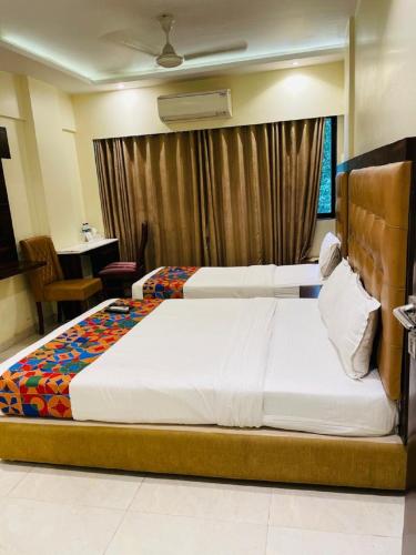 a hotel room with two beds and a desk at Hotel Embassy Park - BKC Mumbai in Mumbai