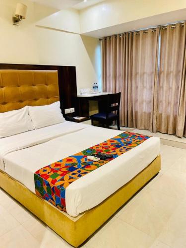 a large bed in a bedroom with a desk at Hotel Embassy Park - BKC Mumbai in Mumbai