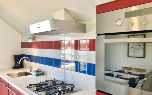 a kitchen with red white and blue tiles on the wall at Roggebroek 13 in Stavoren