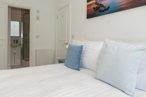 una cama con sábanas blancas y almohadas azules en Church House - 2 Bed-Sleeps 4-TJS21CH, en Ilfracombe