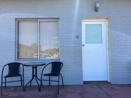 Pingelly的住宿－Pingelly Retreat Motel，一张桌子和两把椅子,旁边是一面墙,有门