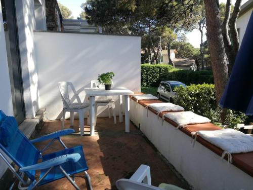 un patio con tavolo e sedie bianchi appesi a un muro di Casa Beatrice a Castiglioncello