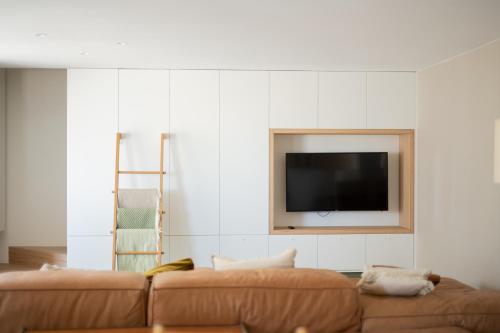 a living room with a couch and a tv on a wall at Vista del Mar Japandi in Koksijde