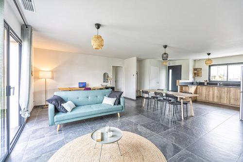a living room with a blue couch and a kitchen at La Marssacoise in Marssac-sur-Tarn