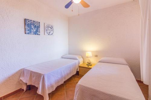 a room with two beds and a table with a lamp at Village Cugnana Verde Lovely Apt -Terrace&Parking! in Cugnana Verde