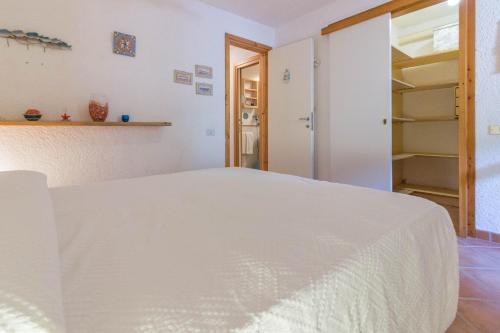 a bedroom with a white bed and a closet at Village Cugnana Verde Lovely Apt -Terrace&Parking! in Cugnana Verde