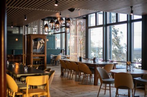 a restaurant with tables and chairs and large windows at Ski-Inn Kultakero in Pyhätunturi