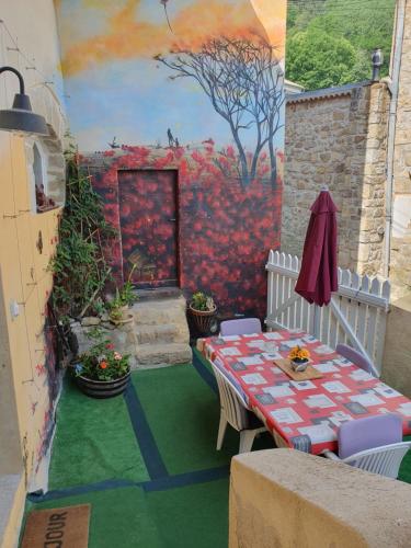eine Terrasse mit einem Tisch und einem Gemälde an der Wand in der Unterkunft Chambres d'hotes de BenSylv pour 4 jours minimums 4 adultes in Labégude