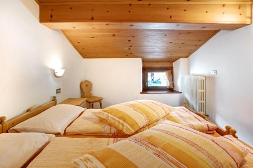 2 łóżka w pokoju z drewnianym sufitem w obiekcie Appartamenti Elisabetta n2 w Livigno