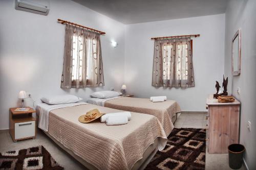 two beds in a white room with curtains at Symi Filoxenia in Symi