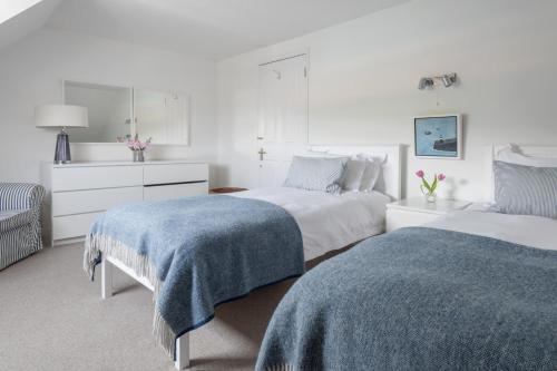 a white bedroom with two beds with blue blankets at Ferry Watch in Salcombe