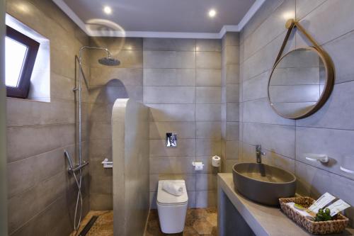 uma casa de banho com um lavatório, WC e um espelho. em Álbero Hotel em Pérama