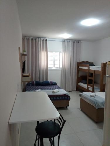 Cette petite chambre comprend deux lits, une table et des chaises. dans l'établissement Kitnet à 300 metros da Canção Nova, à Cachoeira Paulista
