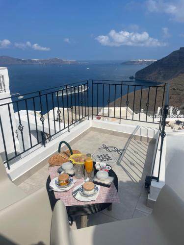 - une table avec de la nourriture sur un balcon avec vue sur l'océan dans l'établissement Doukas Caldera Suites, à Fira