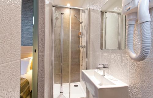 y baño con lavabo y ducha. en Hôtel des Pavillons, en París
